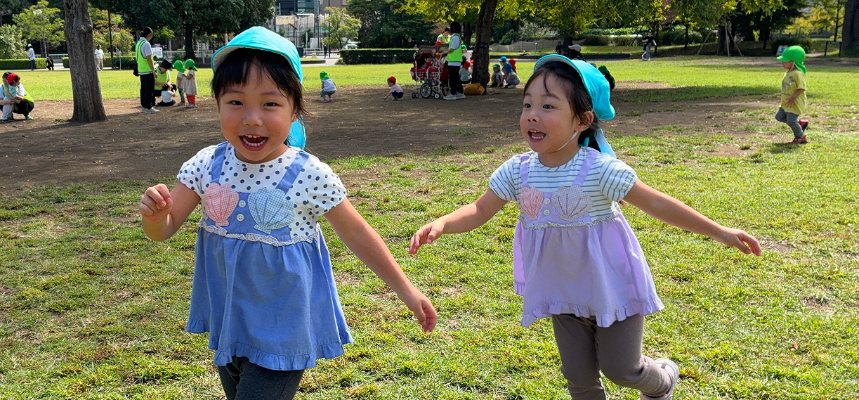 公園の中を笑顔で駆ける２人の女の子