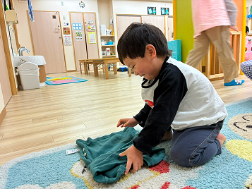 緑のお洋服を自分で畳む園児