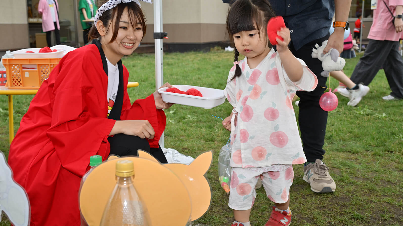 夏祭りの屋台で遊んでいる女の子と先生