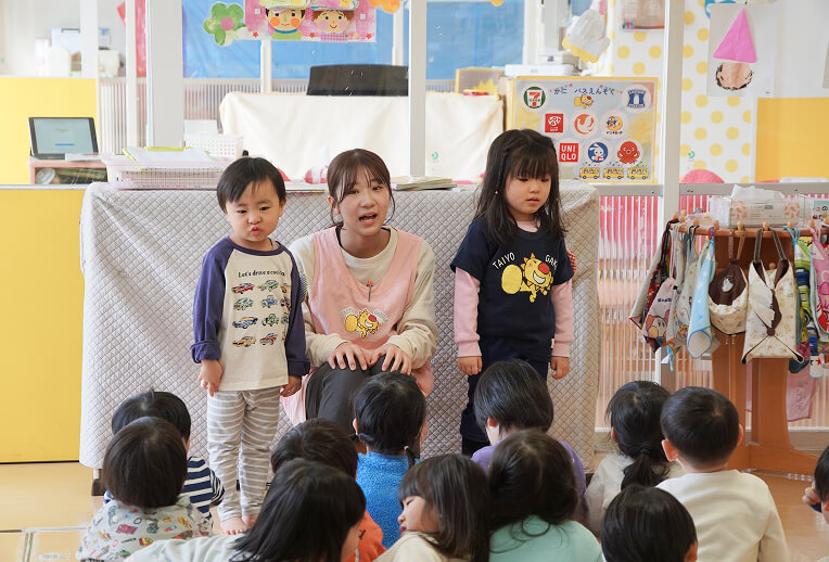 朝の会でみんなの前に立つ先生と二人の児童