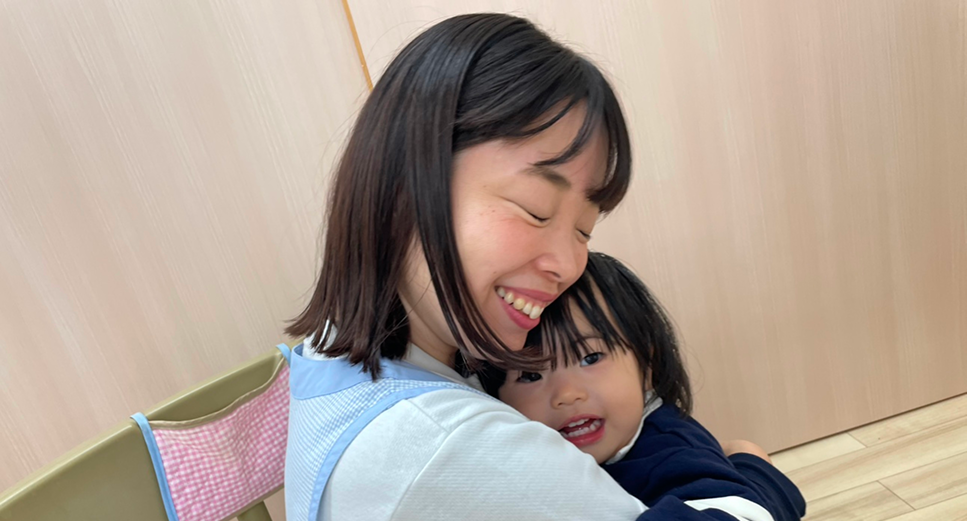 幼児を抱く笑顔の先生