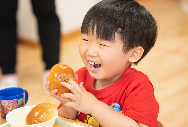 給食でパンを食べる園児