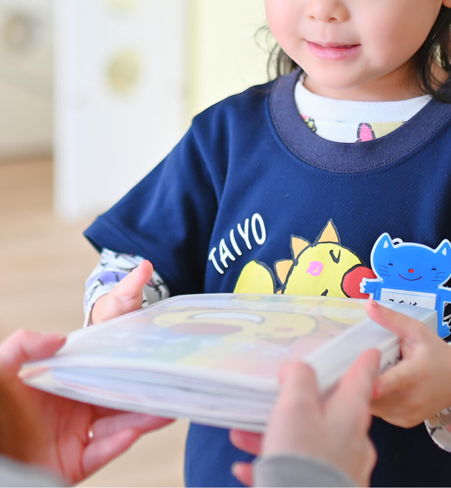 ファイルを大人に手渡す子ども