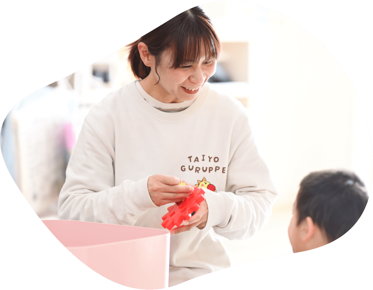 太陽グループのTシャツを着て赤いブロックを持つ先生