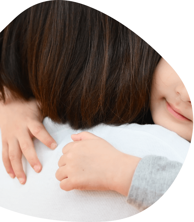 大人に抱きしめられて微笑む子ども